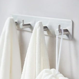 Zelfklevende haakjes van geborsteld metaal met witte handdoeken in een badkamer.