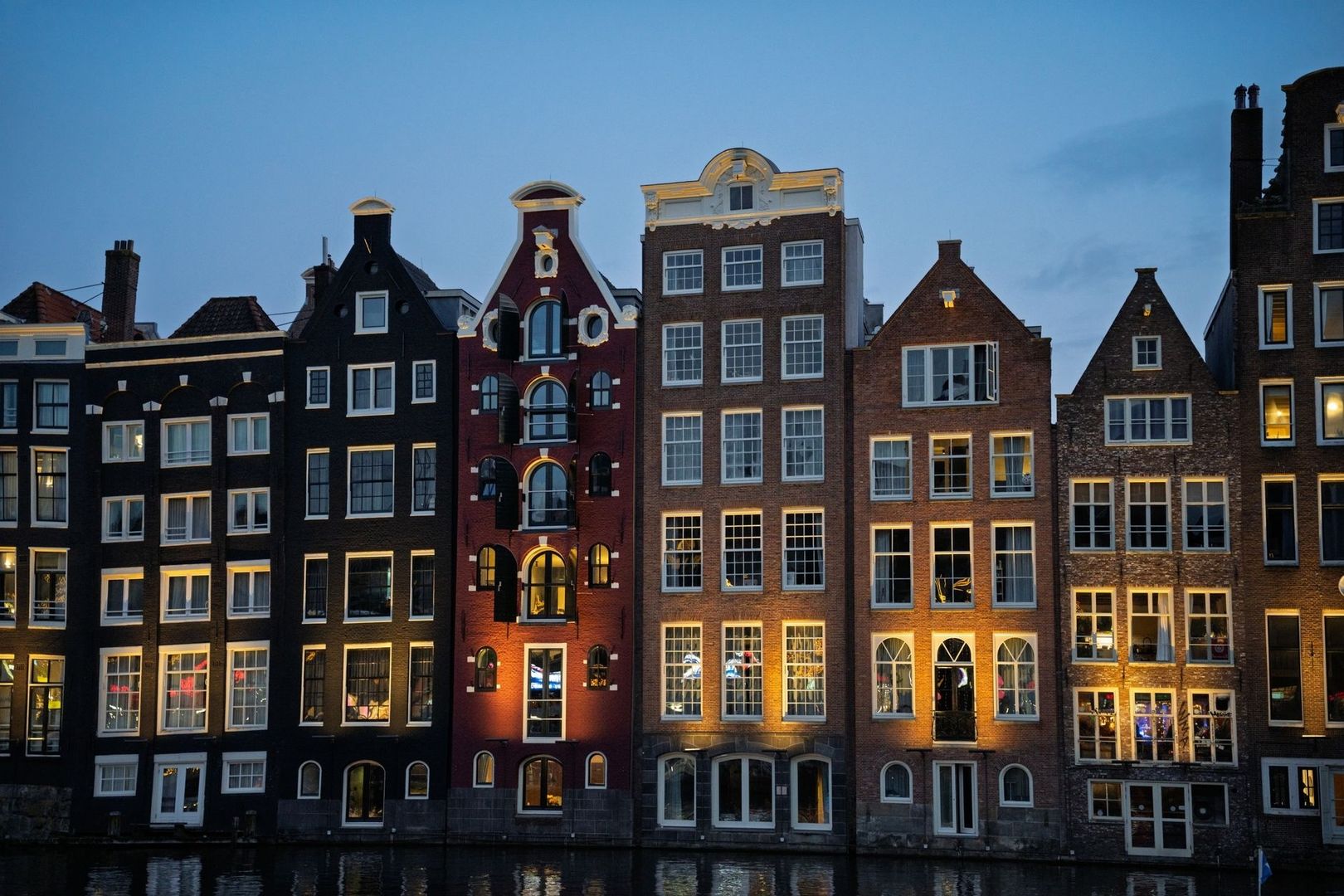 Verlichte ramen van Amsterdamse grachtenpanden bij schemering